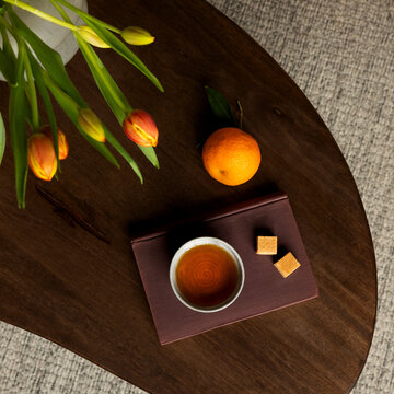 Cozy Overhead View of Tea, Oranges, and Tulips on a Wooden Tabletop, Perfect for Relaxed Lifestyle Concepts
