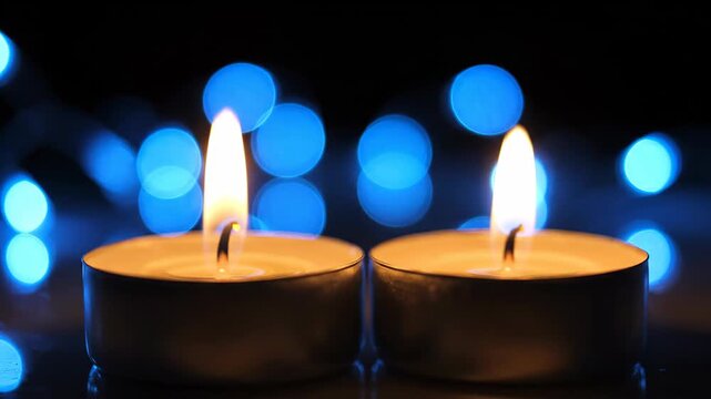 Two burning tea light candles with blue bokeh background