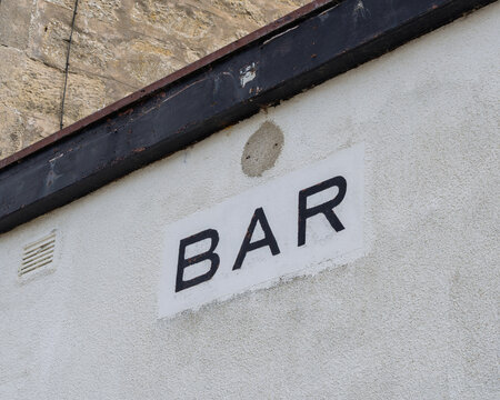 Black and white bar sign painted on a stone wall exterior in the coastal town of Lossiemouth located within the beautiful region of Moray, Scotland