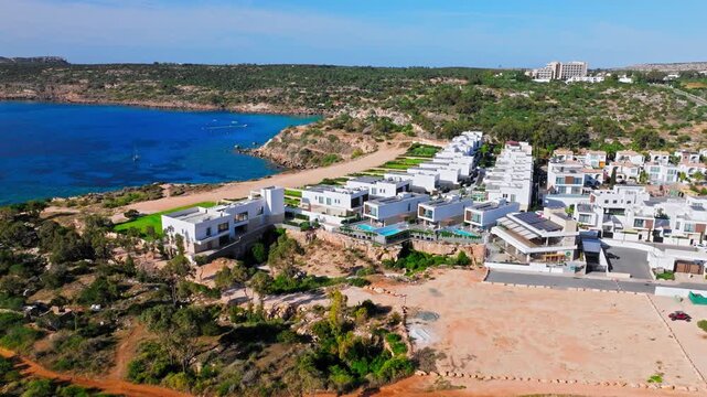 Drone view of Konnos Bay, Cyprus. White seaside hotels, rocky coast and turquoise Mediterranean water form a scenic resort panorama.
