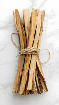 Palo santo sticks bound together with natural twine rest on a clean marble surface to provide a minimalist aesthetic for wellness and meditation.