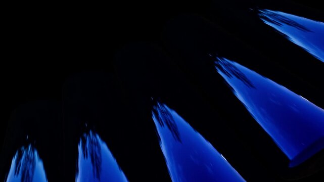 Four blue translucent tubes with reflections arranged diagonally on a black background