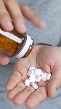 close up hand holding a medicine, with pours the pills out  medicine bottle. Stop drug use Taking Medication Caring for the health care medical concept.
