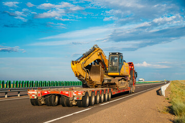 A truck is transporting an excavator along the highway © Павел Чигирь