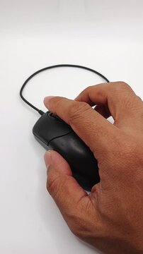 Close-up of a hand scrolling down using the mouse wheel on a wired computer mouse. Concept of web browsing, internet navigation, office work, and computer usage.