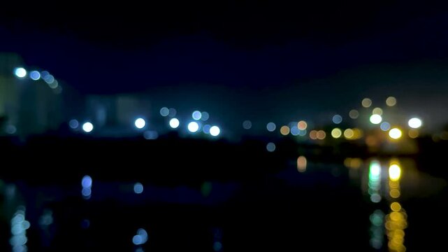 Blurred city lights reflecting on water creating a dreamy nightscape with bokeh effect
