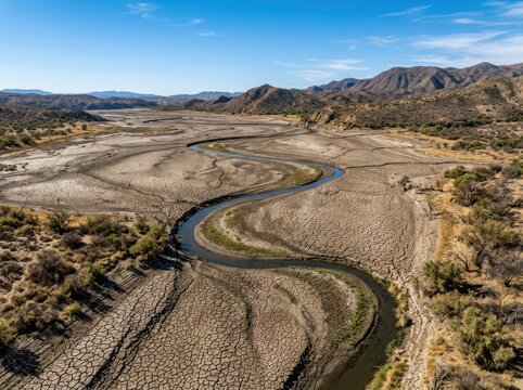 El Ni&ntilde;o desert river landscape with dry cracked earth and mountains