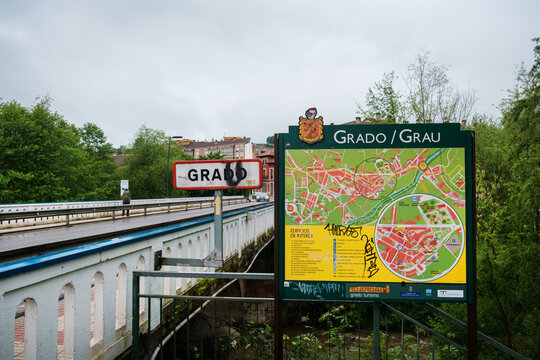 GRADO, SPAIN - May 15, 2025: An official tourist information board with a street map next to the town entrance sign at a bridge crossing along the Camino Primitivo.