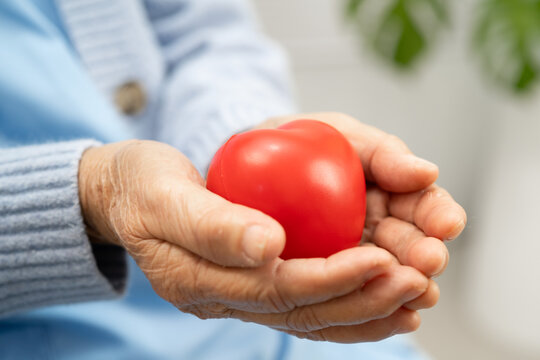 Asian woman holding red heart for health in hospital.