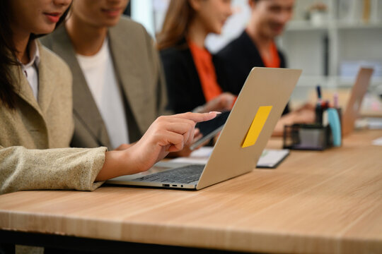 Business team collaborating at office desk with laptop and tablet during workplace meeting