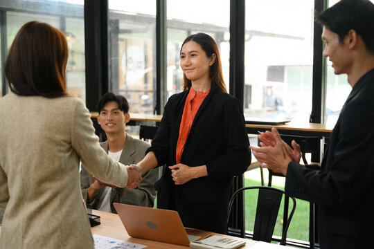 Asian Business Professionals Shaking Hands After Successful Meeting in Modern Office