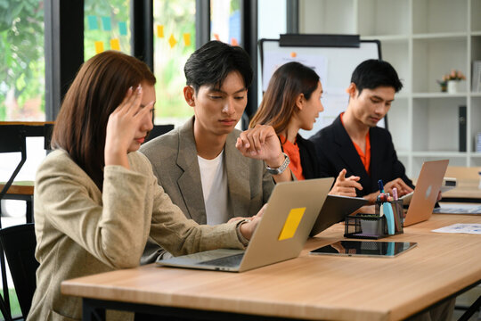 Asian Business Team Collaborating on Laptop in Modern Office Meeting Room