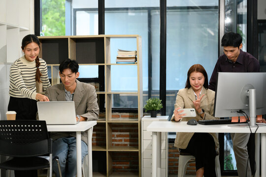 Business Team Planning Strategy Meeting in Modern Office, Asian Colleagues Collaborating at Workstations