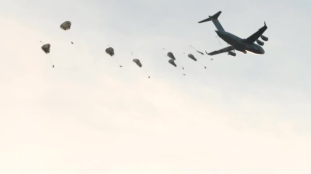 Military Cargo Aircraft Deploying Paratroopers During Airborne Training Exercise Across Open Sky with Precision Tactical Operations.