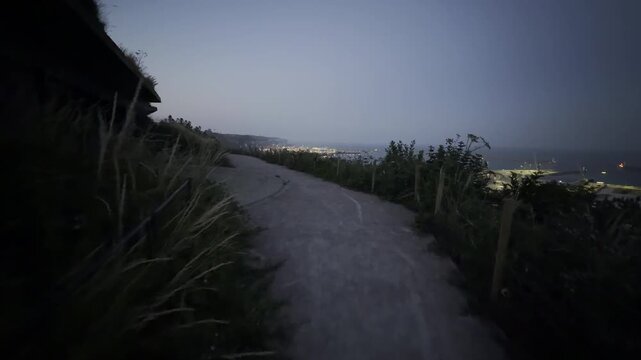 Dark walking path towards seaside town panning