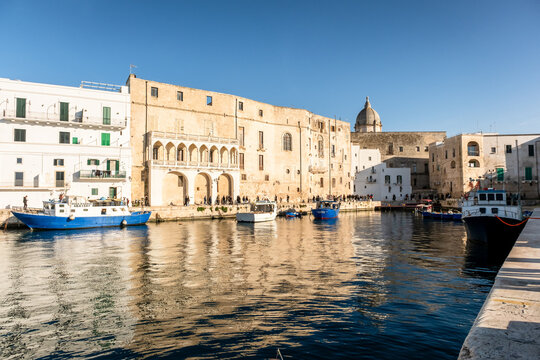 Monopoli, Italy - March 9, 2025: Ancient port (Porto antico) with moored blue boats. 15th century Gate of the ancient port leads from the city to the harbor