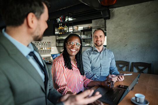 Diverse business team collaborating during informal meeting in cafe