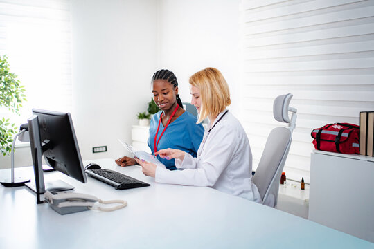 Medical team reviewing documents and discussing health data at desk