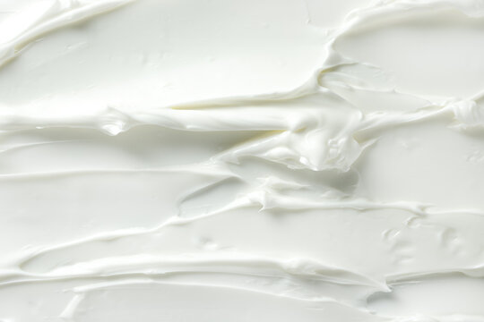 White cosmetic cream texture with glossy swirls and peaks. Smooth whipped moisturizer background for skincare design and beauty branding.
