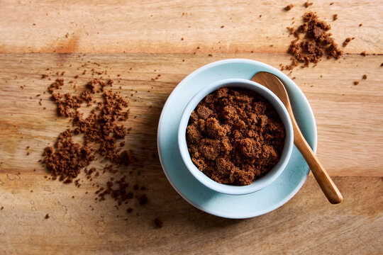 Dark muscovado sugar in a bowl with wooden spoon on rustic wooden table. Natural unrefined muscovado sugar for baking and cooking.