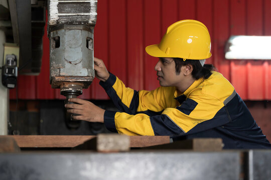 Manufacturing industry and factories. Heavy industry machine. Maintenance or repair industrial machine. Asian male factory engineer inspecting or maintenance vertical drilling machine in factory