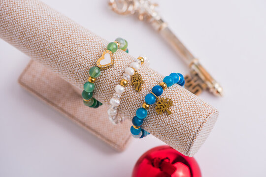Handmade jewelry collection including gold earrings, beaded bracelets, and rings displayed on fabric stands for commercial product showcase.