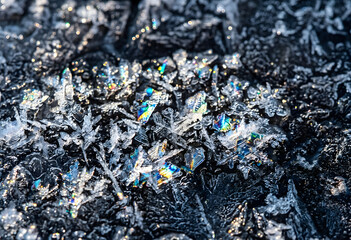 Obraz premium Iridescent ice crystals sparkling on dark frozen ground