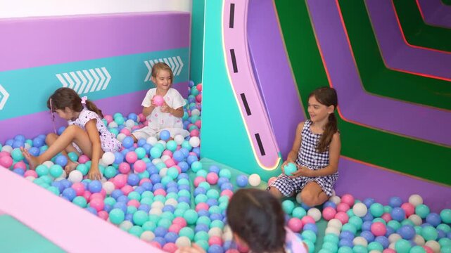 Cheerful children throwing plastic balls and laughing together in a modern indoor playground