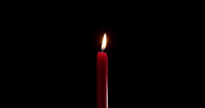 Tall red candle burning steadily in a quiet dark room. The clean flame of this wax candle cuts through shadows. This glowing candle symbolizes faith, peace, and festive overlay design.