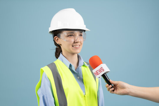 Smiling woman engineer giving speech interview to microphone reporter
