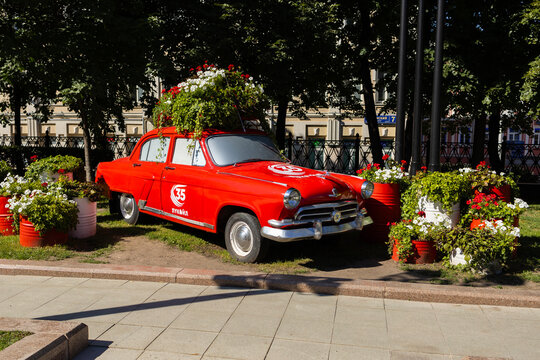 Red vintage soviet car gas-21 volga decorated with blooming flowers in city park. Russia, Moscow 19.07.2026
