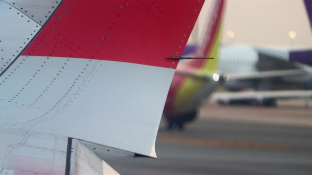 Close-Up Airplane Wing Detail at Airport With Taxiing Aircraft and Runway Background