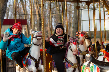 Two school-age children in winter clothes ride on a carousel in the park in autumn © Светлана Лазаренко