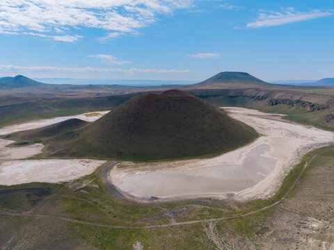 Meke Crater Lake in Karapnar, Konya, features a remarkable volcanic landscape with a large, lush crater surrounded by arid plains and distant hills, creating a unique travel destination in Turkey.