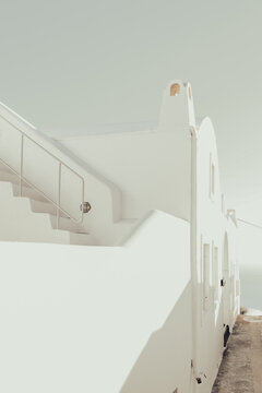 Bright white minimalist architecture in Santorini, Greece, featuring clean lines, soft shadows, and coastal light that evoke Mediterranean serenity and modern elegance.