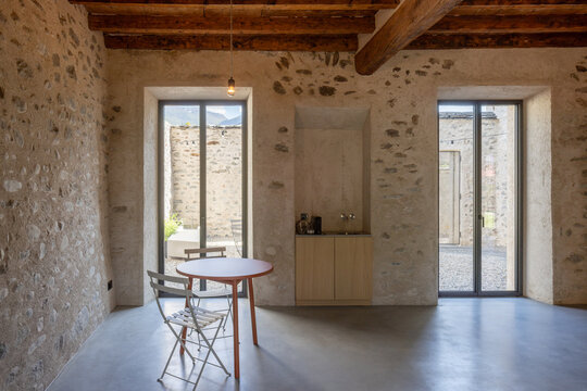 The interior of a refurbished room in an old house with stone walls. Inside, there is a table and a sink for washing your hands and making coffee. A warm and cosy space.