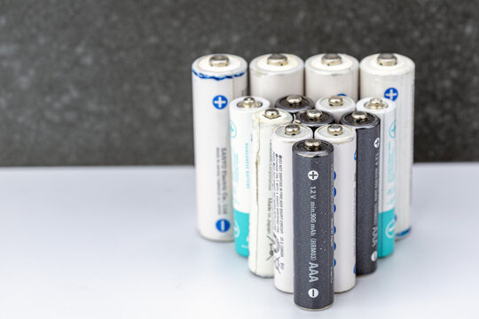 Close-up collection of mixed AAA and AA rechargeable NiMH batteries standing upright on white surface, showing positive terminals and labeled 1.2V min 900mAh