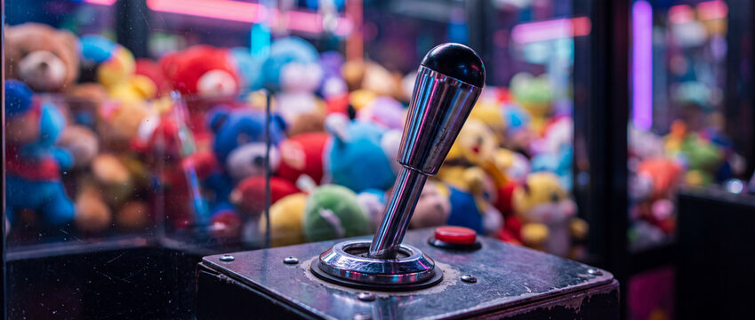 Claw machine joystick with plush prizes in neon arcade lights, colorful arcade game closeup
