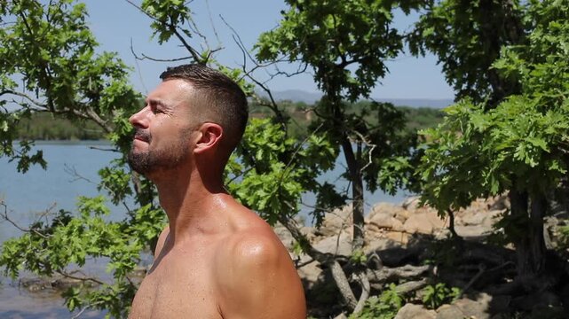 Shirtless Muscular Man Exercising with Resistance Bands on Sunny Beach