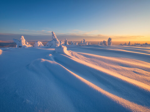 Magical evening landscape of a winter nature at sunset with a glowing sky. Winter landscape. Deep snowdrifts, freezing frost and snow-covered trees under atmospheric evening light.