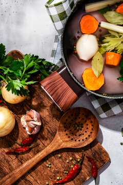 Homemade chicken soup preparation process. Organic poultry meat with root vegetables, chili, and spices.