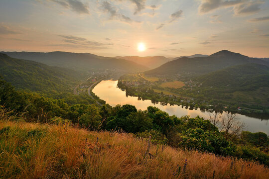 Stunning golden sunrise reflecting on the surface of the Elbe river as seen from a high grassy lookout