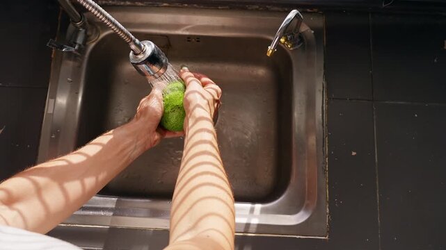 Overhead View of Person Washing Green Avocado in Kitchen Sink in Slow Motion, Fresh Produce Hygiene and Healthy Nutrition