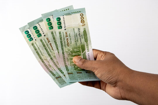 Human hand holding four Bangladeshi 500 taka banknotes isolated on white background. Paper currency notes for cash payment, retail transaction, and shopping.