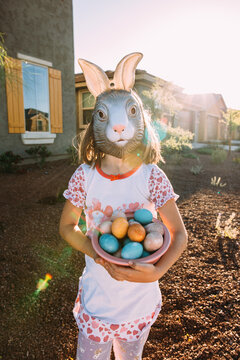 girl wearing easter bunny mask with easter eggs