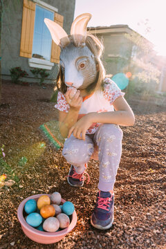 Girl wearing bunny mask with easter eggs