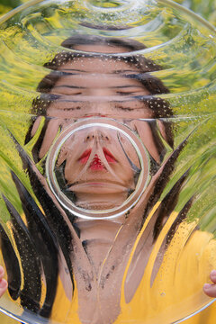 art portrait of face of a young woman behind glass plate