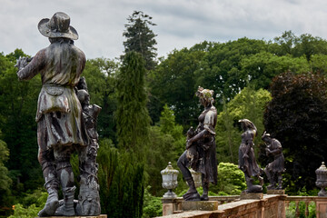 Obraz premium Classical statues set among lush garden trees and hedges