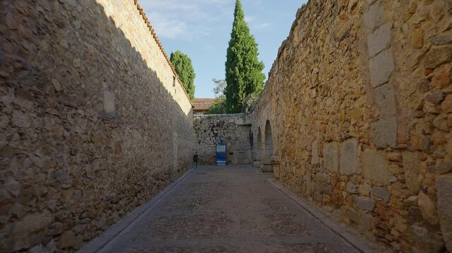Narrow medieval cobblestone street enclosed by ancient stone walls in the historic old town of Segovia Spain