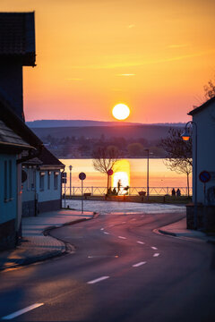 Geschl&auml;ngelte Stra&szlig;e in Richtung eines See bei Sonnenuntergang